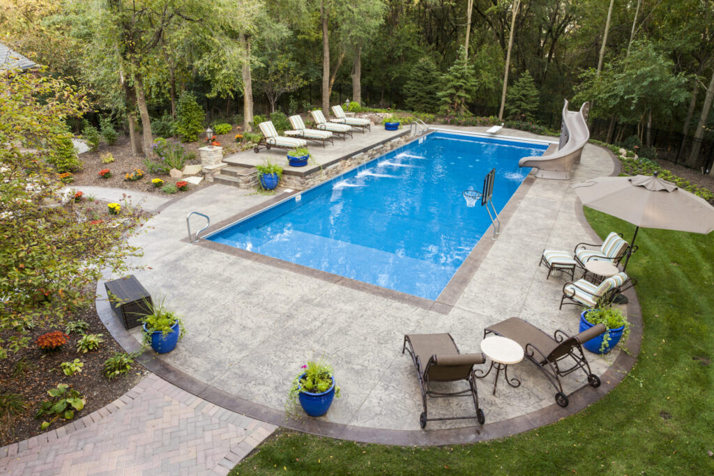 privacy backyard swimming pool with lush greenery and trees surrounding, cozy poolside lounge chairs and flower pots decoration