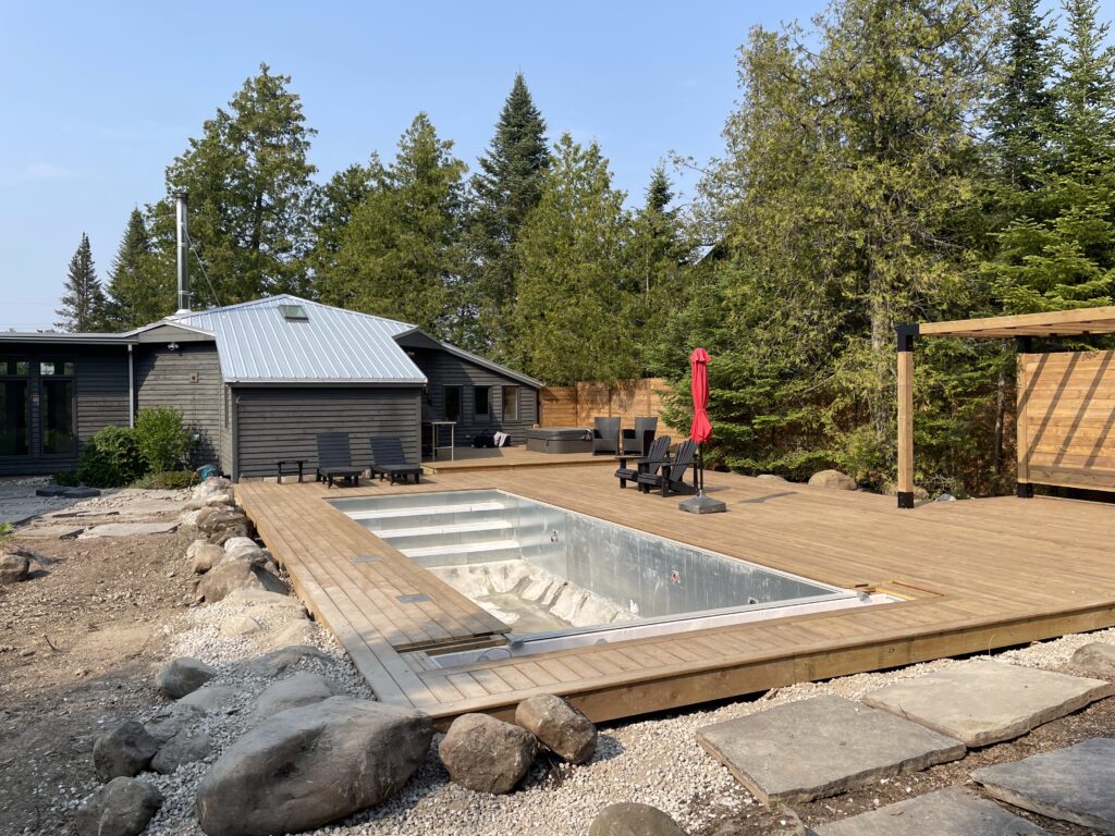backyard of modern home. inground pool with wood deck surround under construction, no vinyl liner, or vinyl liner being replaced.