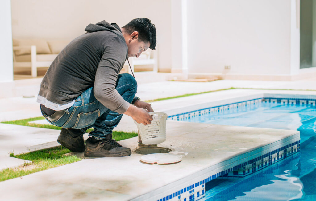 Worker removing trash from swimming pool filter basket. Man cleaning swimming pool garbage filter.