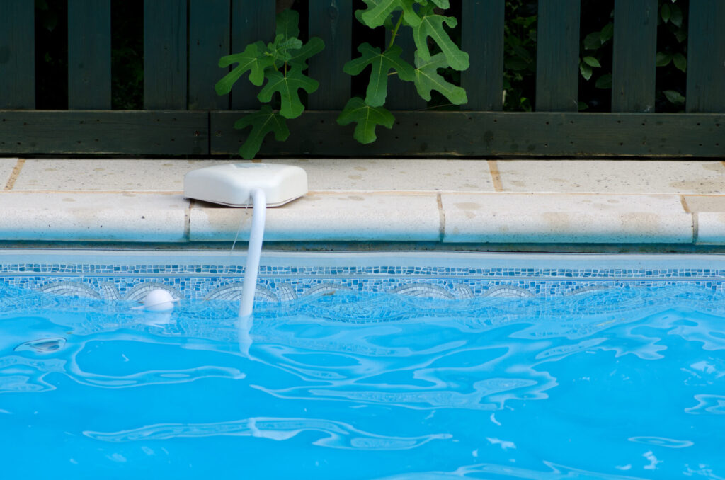 Swimming pool alarm positioned on the side of a home swimming pool.
