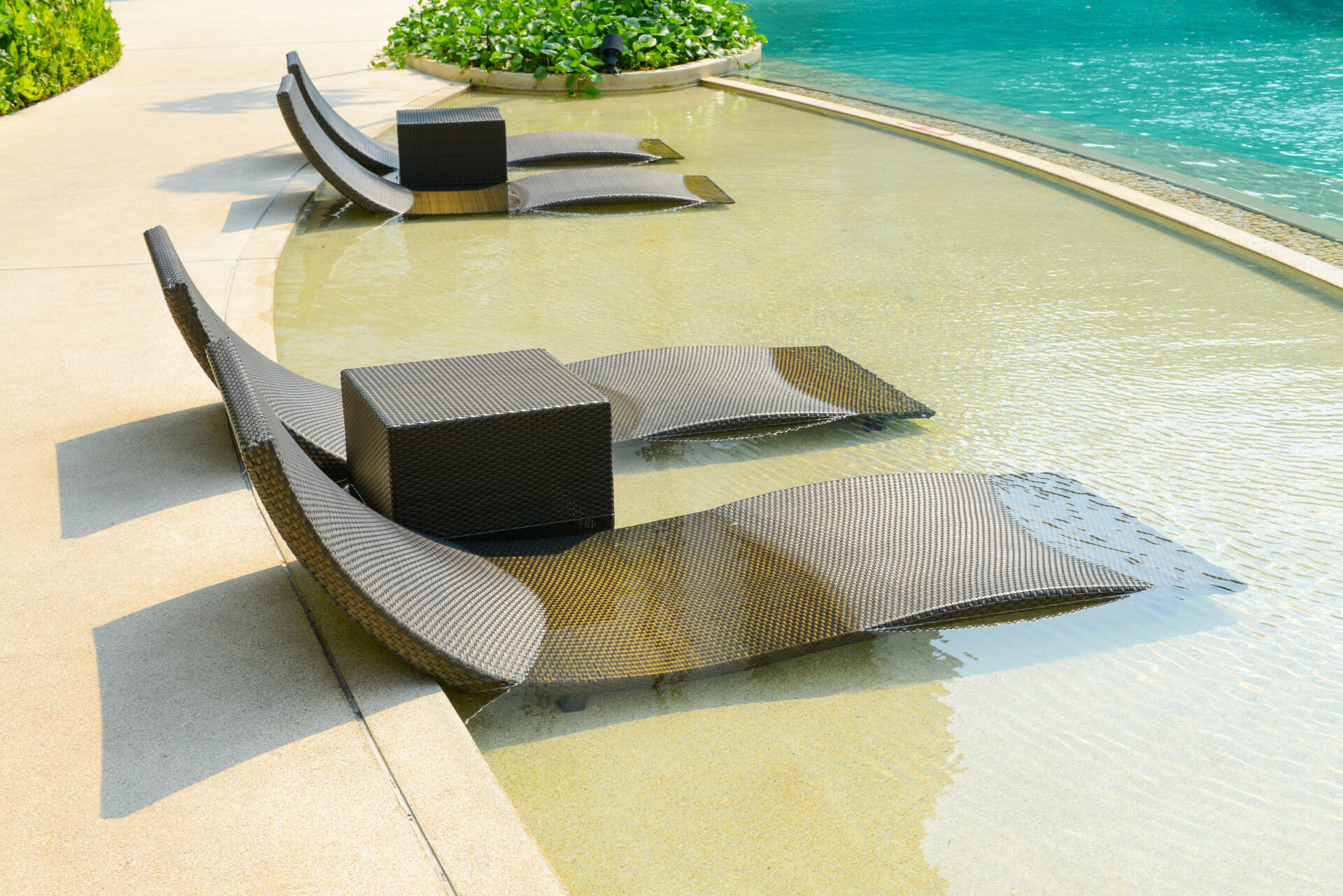 Beach chairs in luxury swimming pool at tropical hotel resort, relaxing and leisure time in the pool.